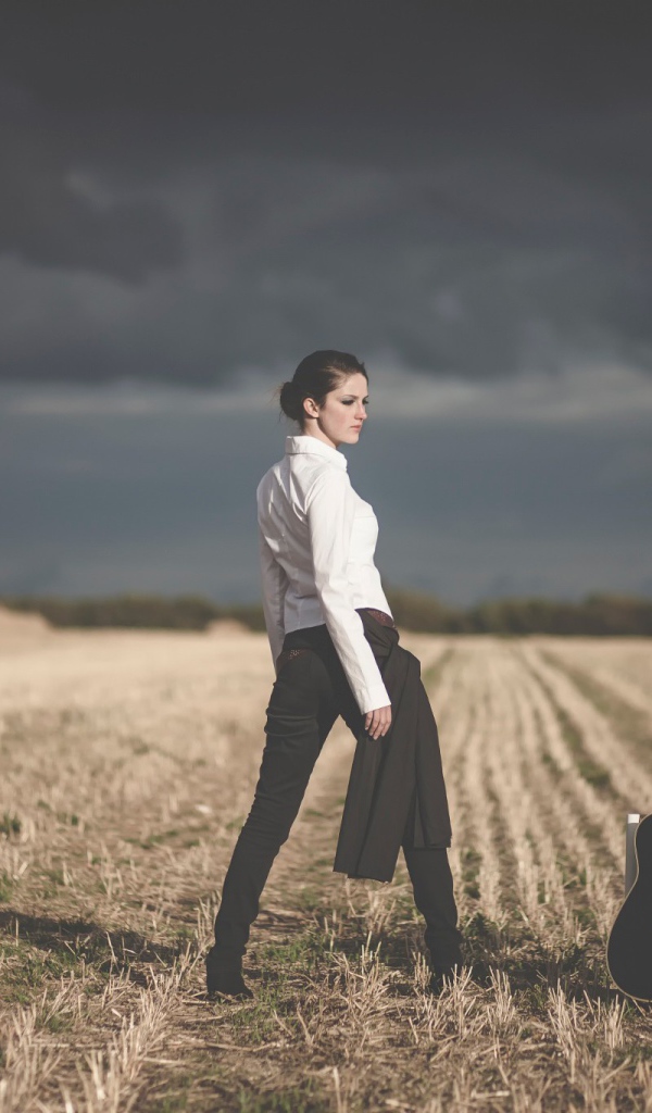 Девушка в поле у стула с гитарой