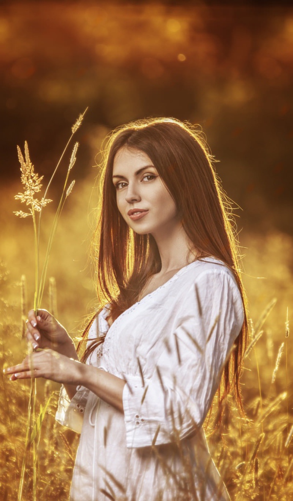 A girl in a white dress holding a spikelets