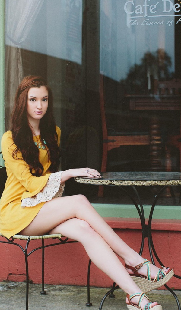 Девушка сидит за столиком уличного кафе