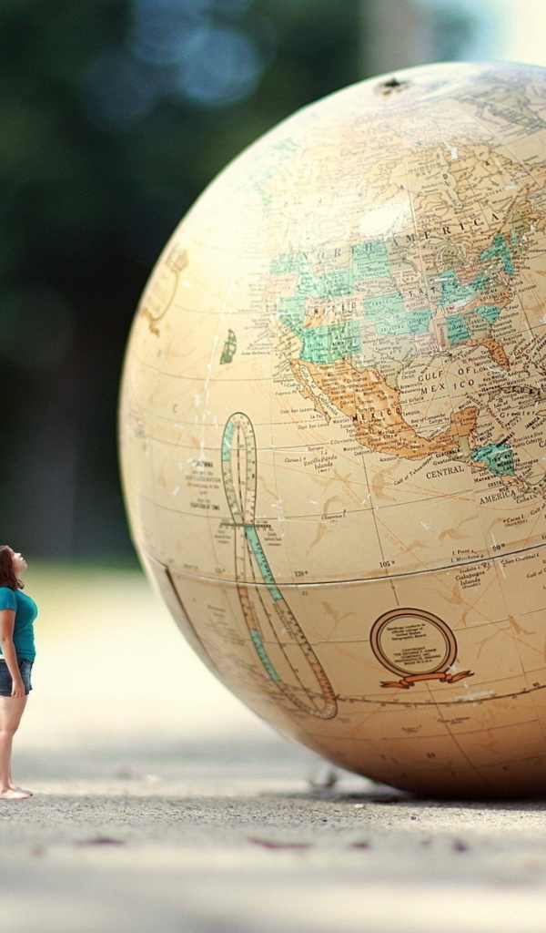 Девушка стоит перед огромным глобусом