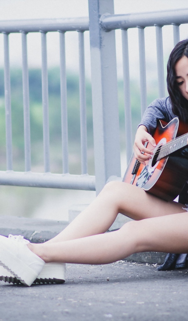 Азиатка брюнетка с гитарой на мосту