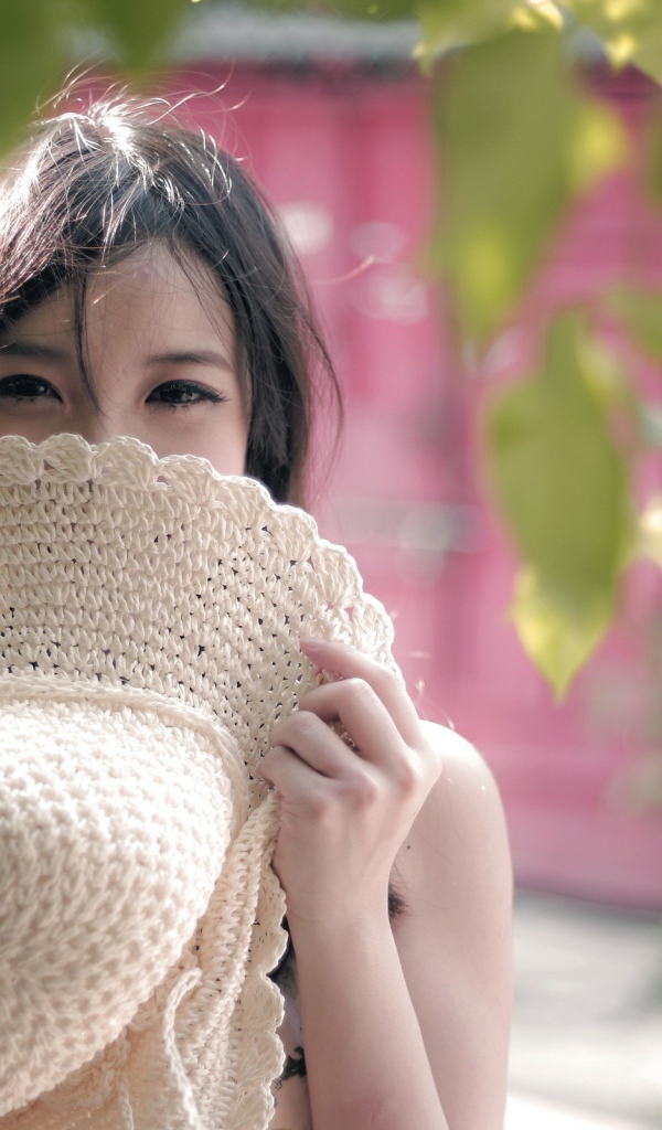 Азиатская девушка прикрыла лицо шляпой