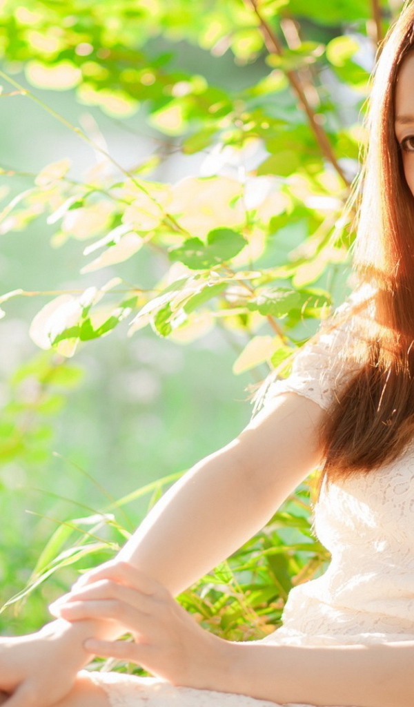 Азиатская девушка прислонилась спиной к дереву