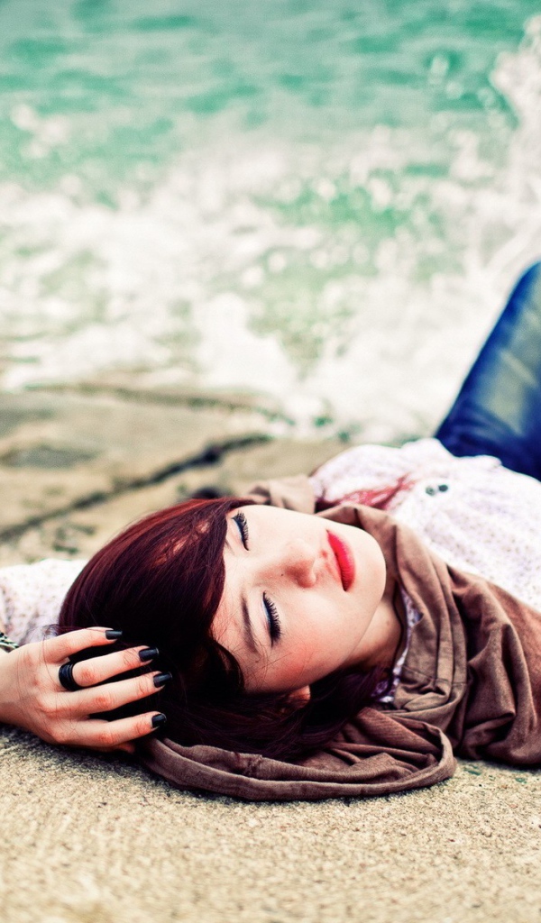 Босая девушка в джинсах лежит на набережной