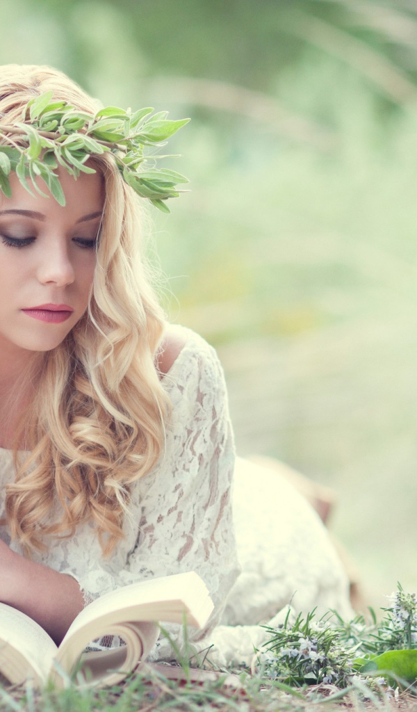 Блондинка в зеленом венке читает книгу