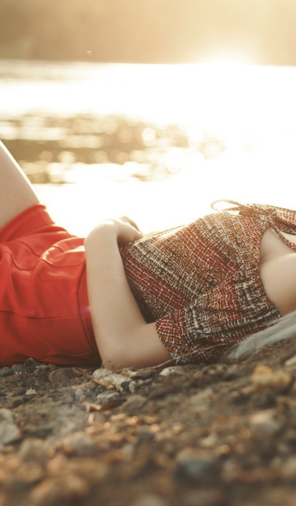 Блондинка в очках лежит на берегу озера