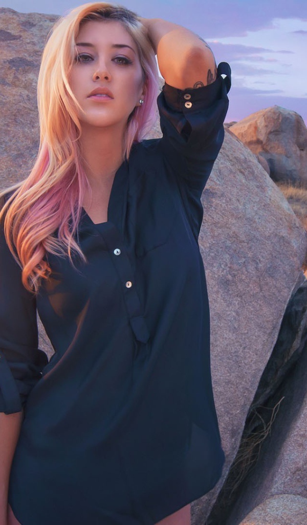 Блондинка стоит у большого валуна