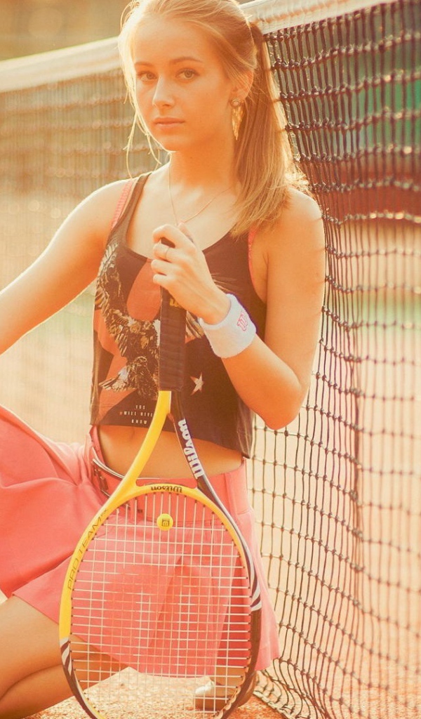 Блондинка теннисистка у сетки на площадке