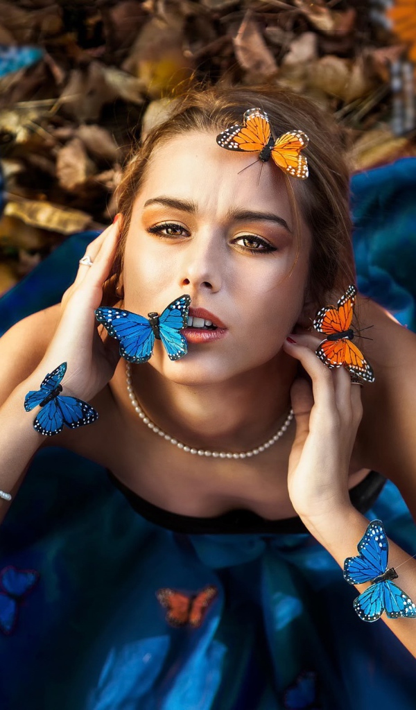 Голубые и оранжевые бабочки на девушке