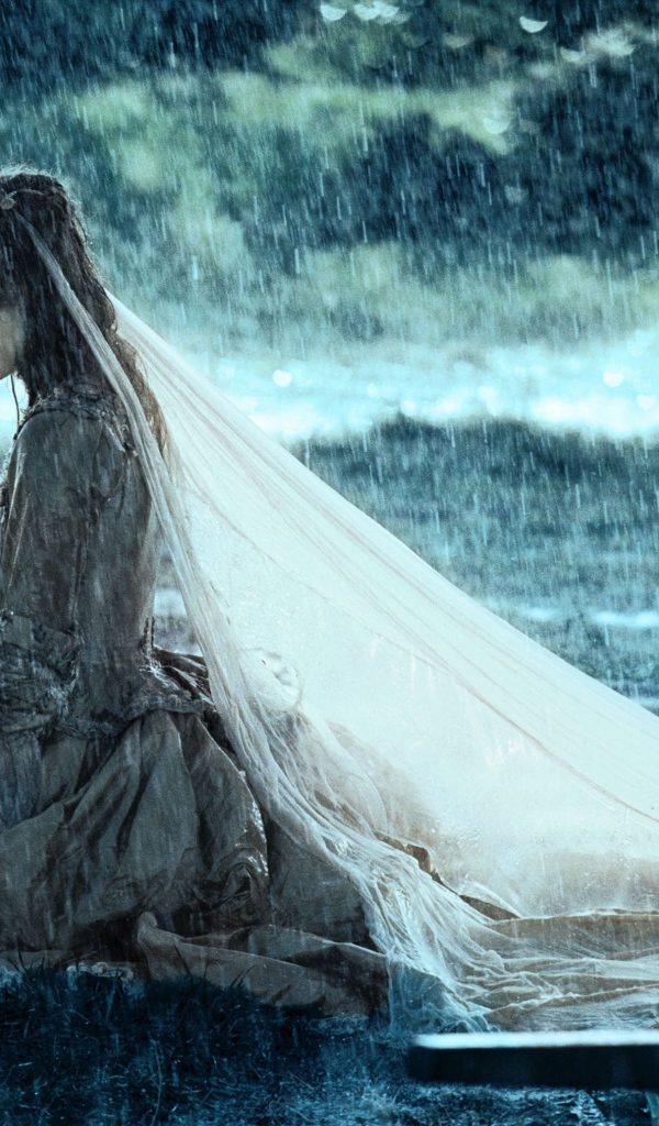 Невеста сидит на коленях под дождем