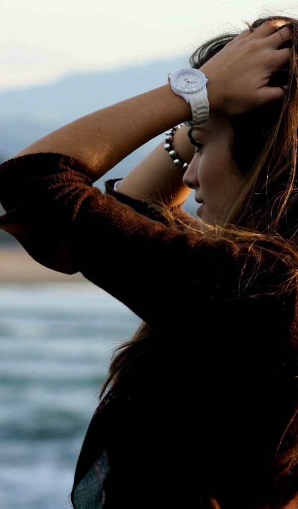 Шатенка с длинными волосами поправляет прическу