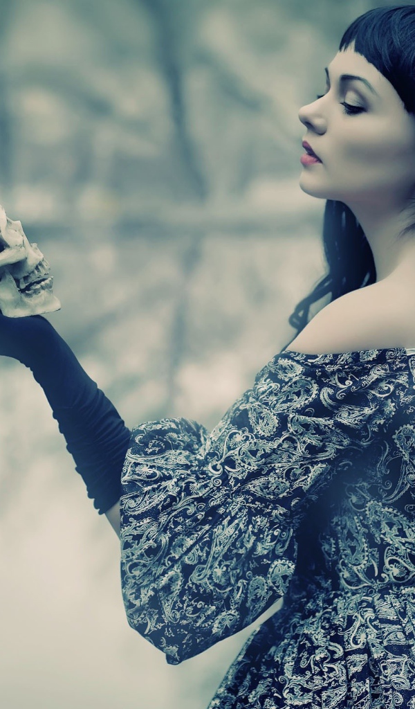 Брюнетка держит в руке череп