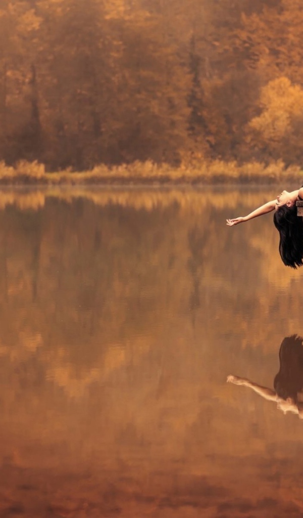 Брюнетка лежит на пирсе на озере