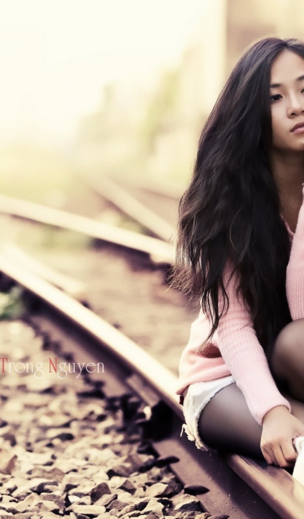 Брюнетка сидит на холодных рельсах