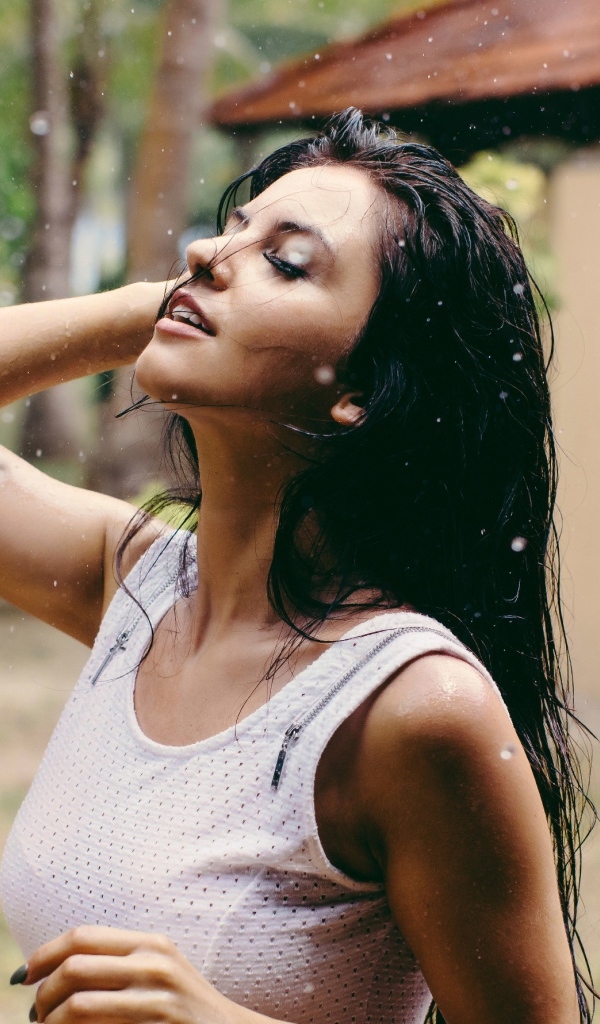 Брюнетка подставляет лицо под капли дождя