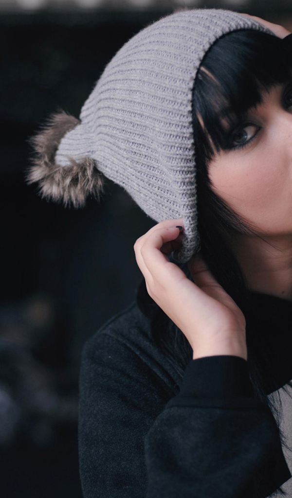 Брюнетка одевает вязаную шапочку