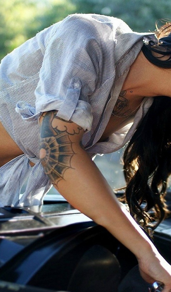 Брюнетка с татуировками ремонтирует машину