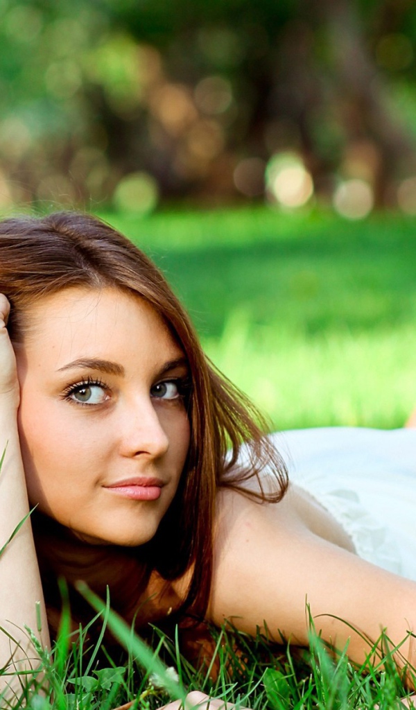 Беззаботная девушка лежит на зеленой траве