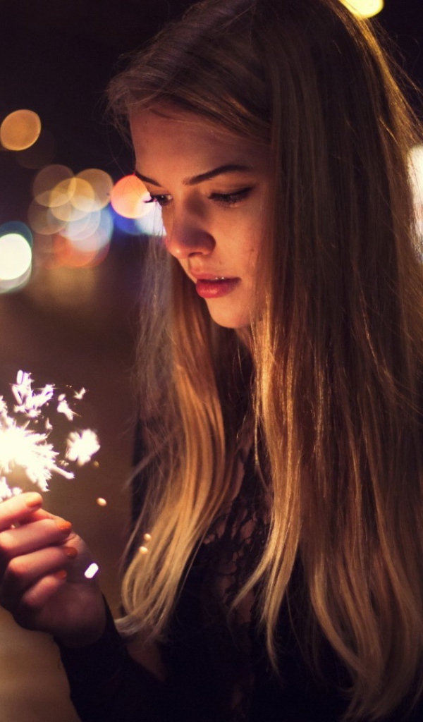 Девушка держит в руке бенгальский огонь