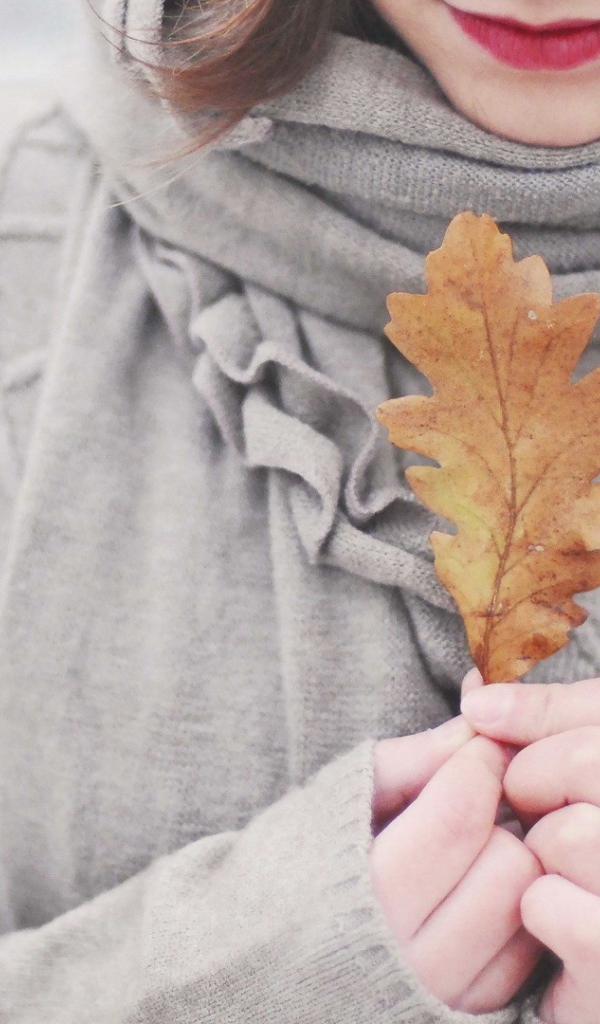 Девушка держит в руках желтый лист