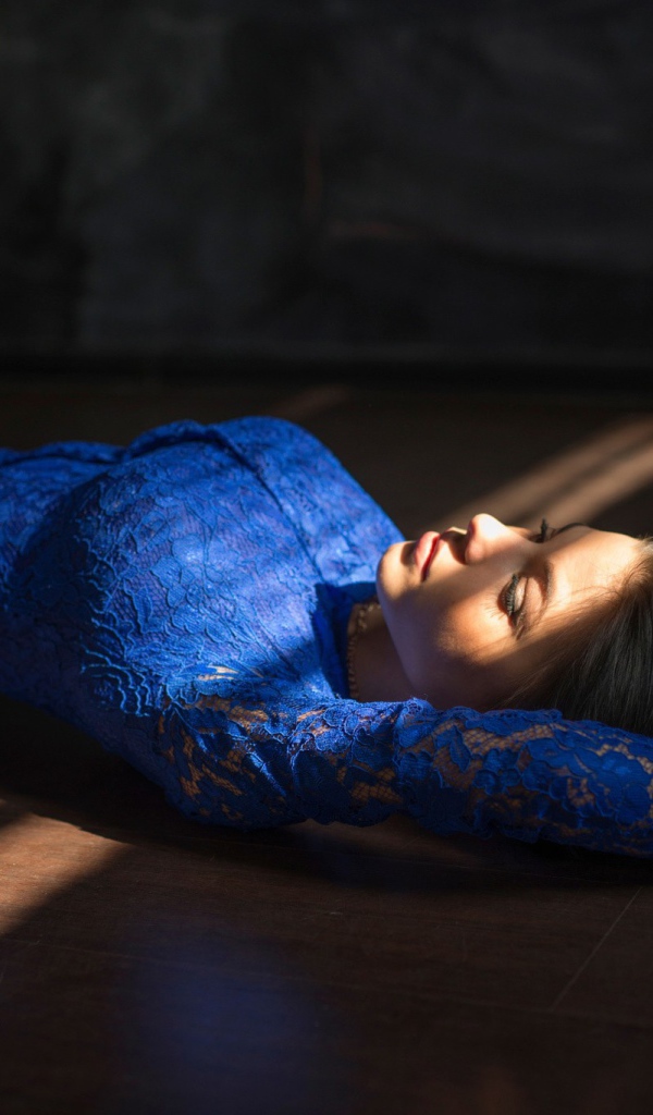 Девушка в голубом кружевном платье лежит на полу