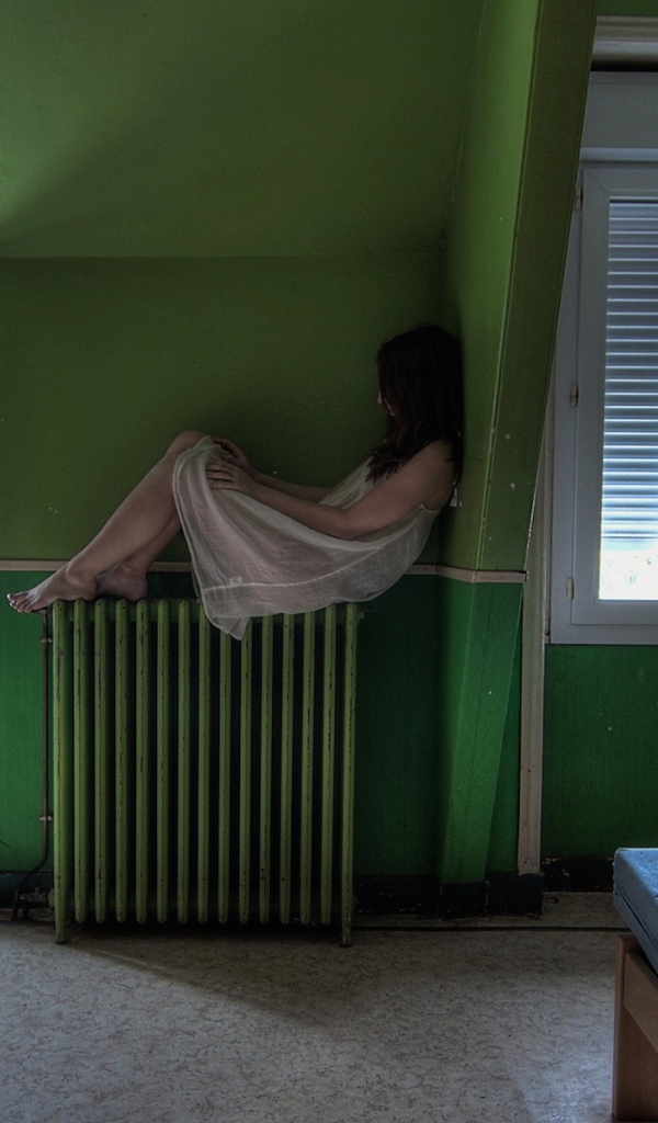 Девушка в ночной рубашке сидит на батарее
