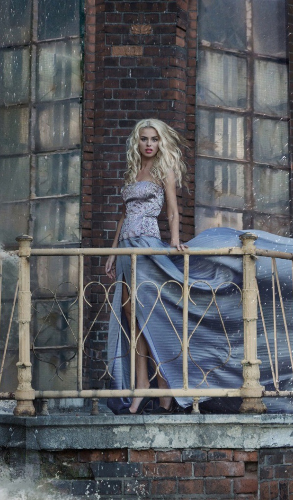 Девушка в платье стоит на балконе маяка