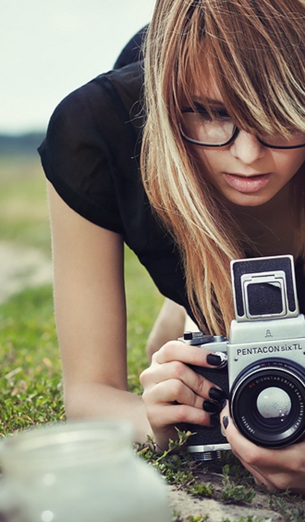 Девушка в очках фотографирует траву