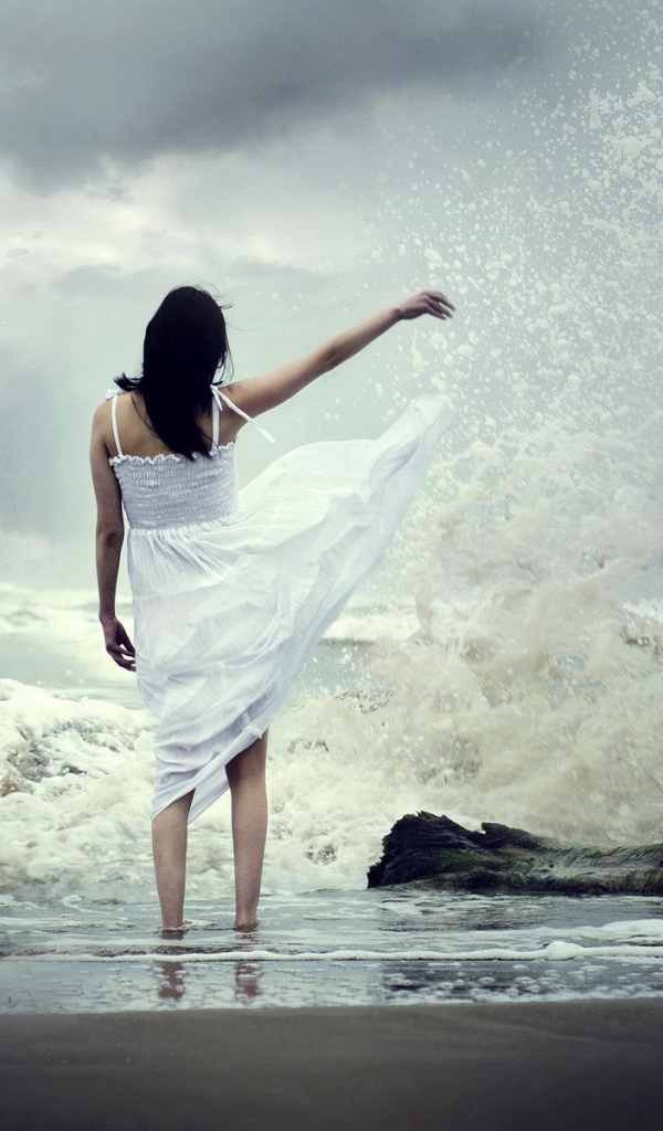 Девушка в белом платье среди брызг прибоя