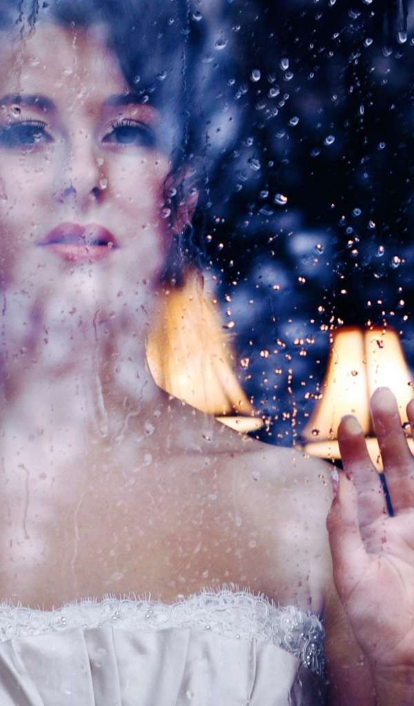 Девушка в белом платье за мокрым стеклом