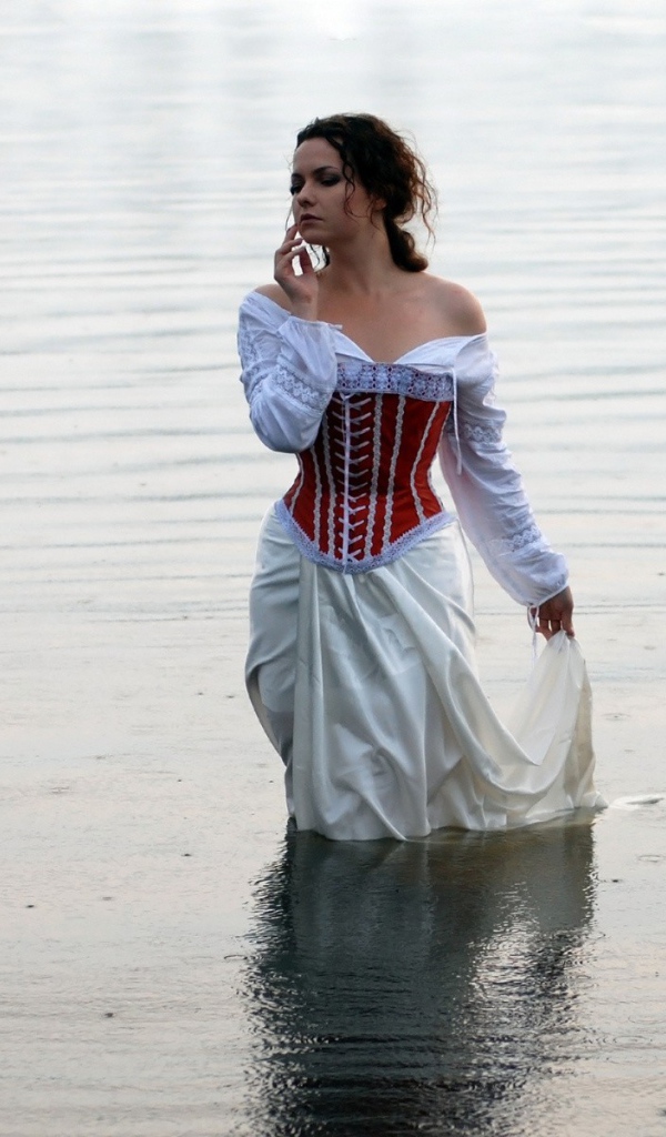 Девушка в белом платье стоит в воде