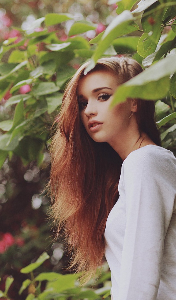 Девушка в белом платье гуляет в саду