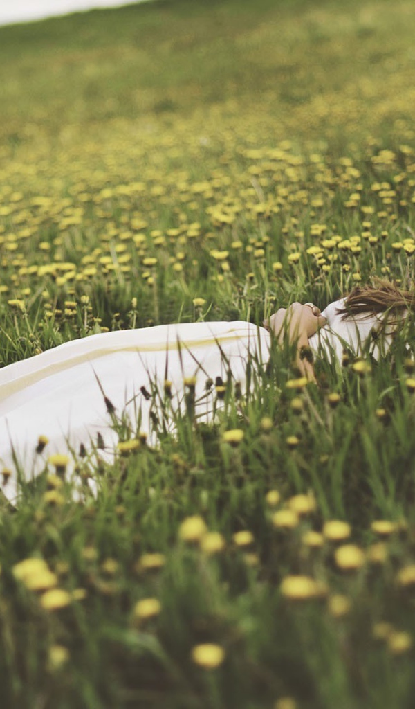 Девушка лежит в поле среди одуванчиков