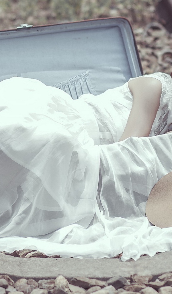 Девушка лежит в чемодане на рельсах