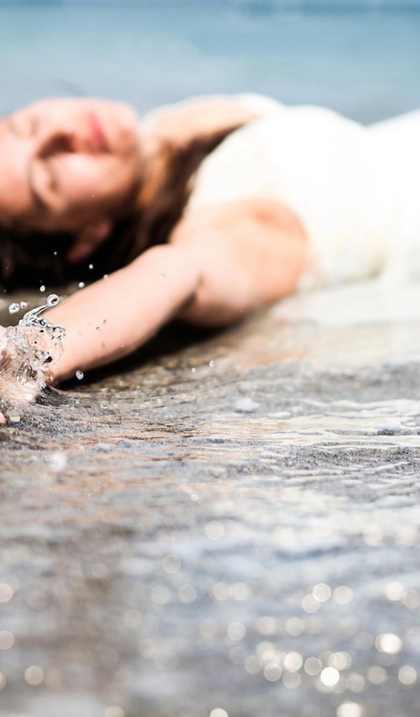Девушка лежит в волне прибоя