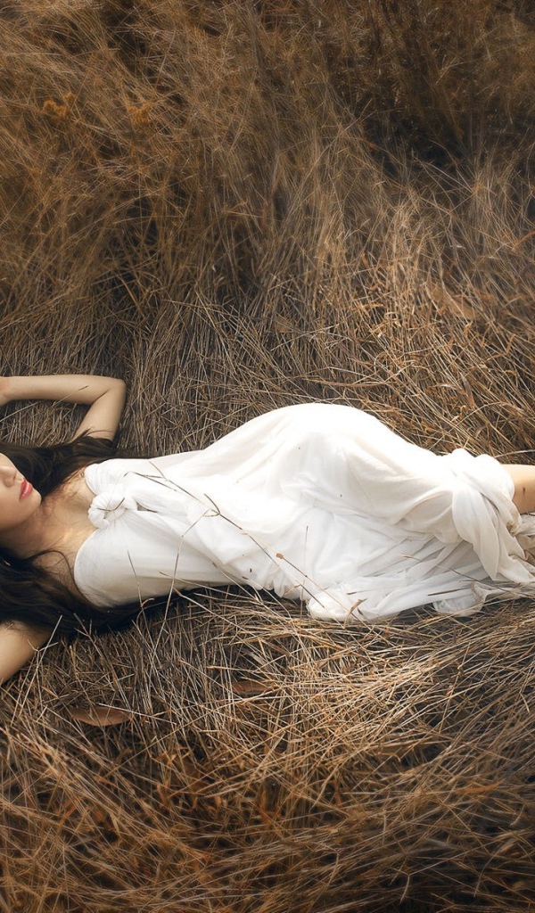 Девушка лежит на сухой траве