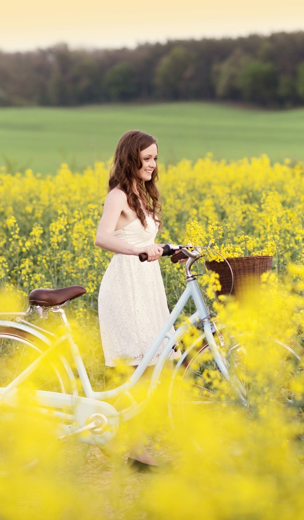 Девушка на велосипеде среди желтых цветов