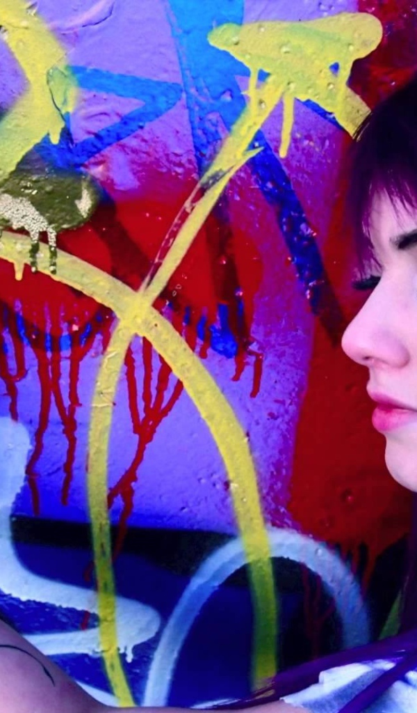 Девушка рисует граффити на стене