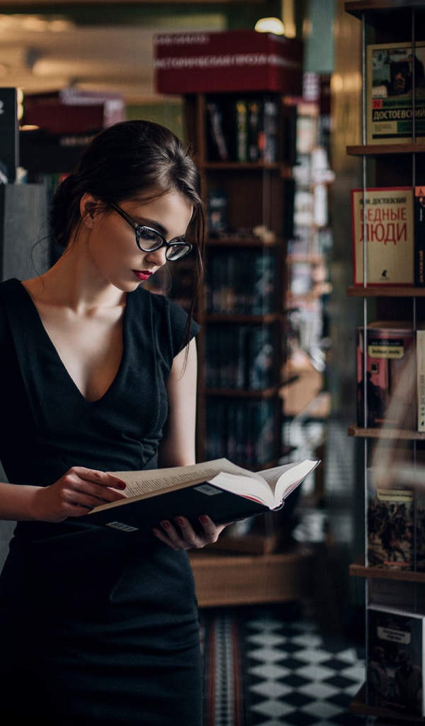 Девушка читает среди книжных полок