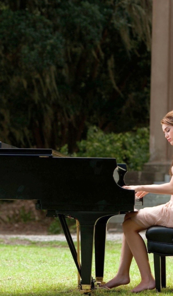 Девушка сидит за роялем на улице