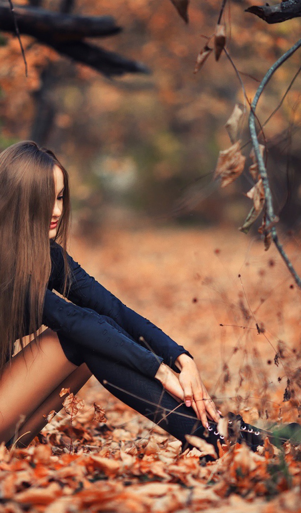 Девушка сидит на осенней листве