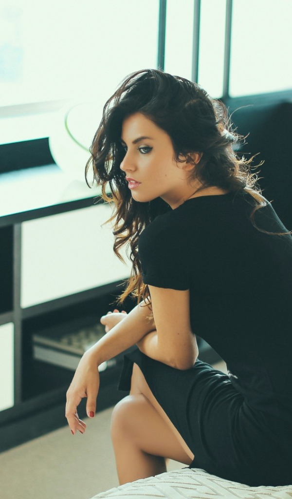 Девушка сидит на кровати перед телевизором