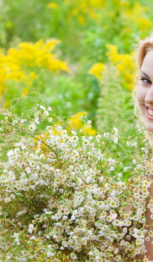 Девушка улыбается, держа в руках букет ромашек