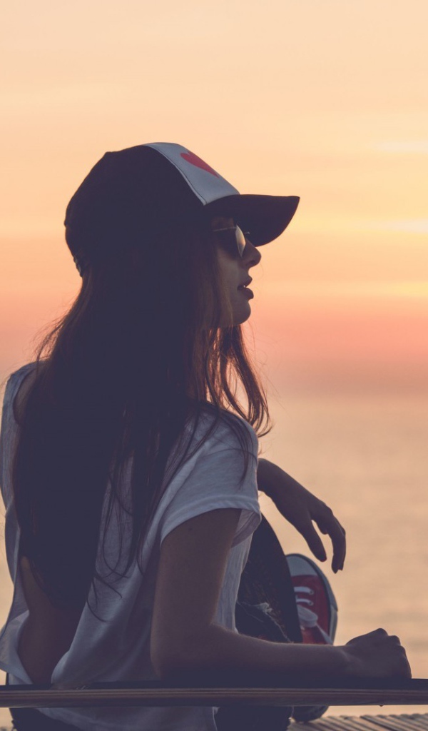 Девушка смотрит на закат на пляже