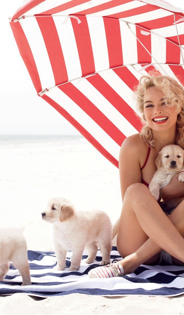 Девушка с собачками отдыхает на пляже под зонтиком