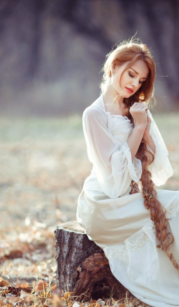 Девушка с косой сидит на пеньке