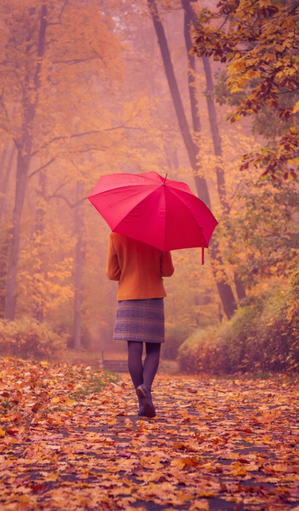 Девушка с красным зонтом идет по аллее