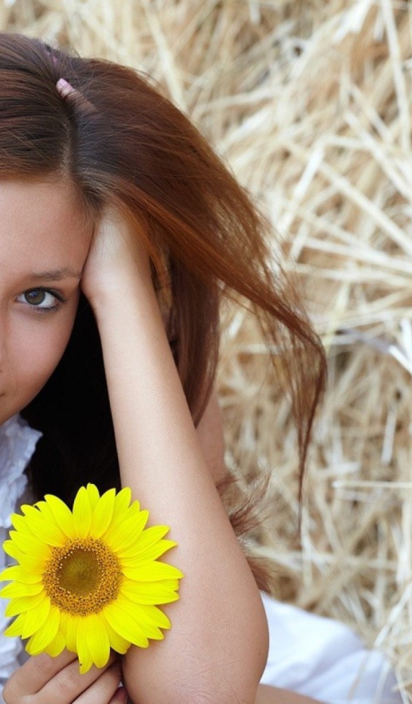 Девушка с желтым цветком сидит на сене