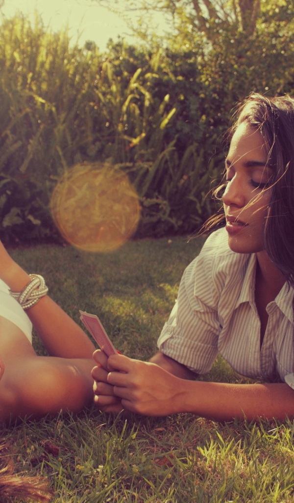 Девушки играют в карты на газоне