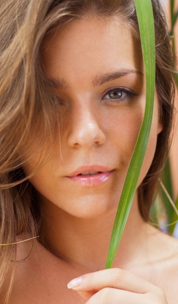 Зеленые листья на лице у девушки